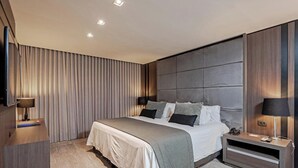 Een moderne hotelkamer met een groot bed, hoofdeinde, nachtkastjes en een flatscreen televisie.