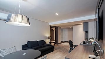 Una habitación de hotel moderna con un sofá, una mesa de comedor, una lámpara y un televisor.