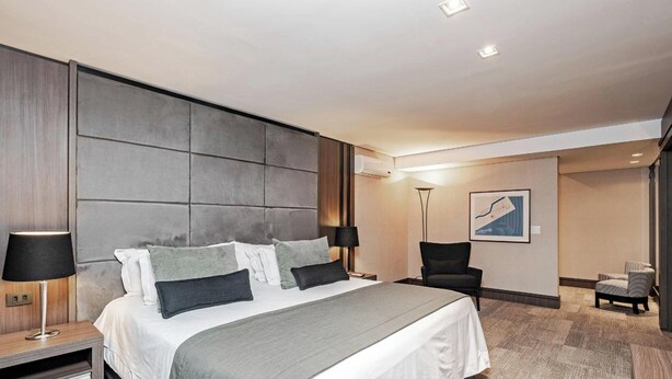 Een hotelkamer met een groot bed, bedlampjes, een bureau, een stoel en een klein tafeltje.