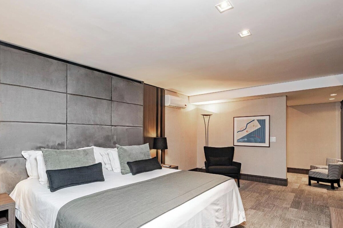 Une chambre d’hôtel avec un grand lit, des lampes de chevet, un bureau, une chaise et une petite table.