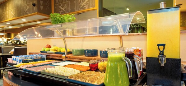 Un buffet proposant une variété de plats et un distributeur de jus.