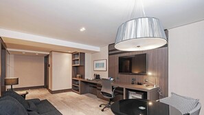 Une chambre d’hôtel moderne équipée d’un bureau, d’une chaise, d’un canapé et d’un grand miroir.