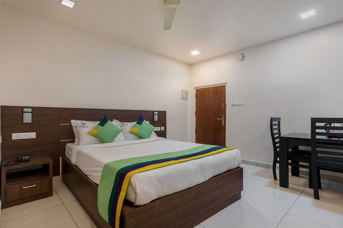 A neatly arranged hotel room with a bed, bedside table, and a desk with a chair.