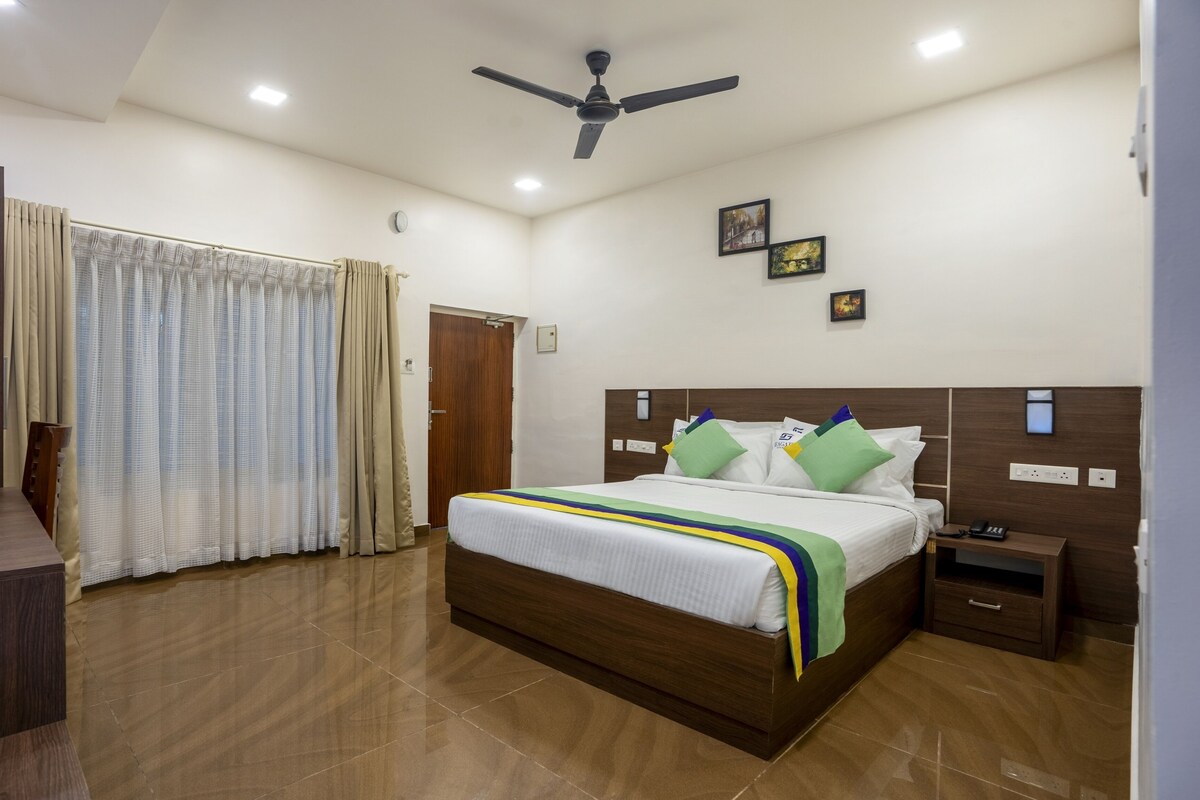 A hotel room with a bed, bedside table, and a desk with a chair.