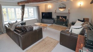 A spacious living room with a fireplace, a television, and a large window. - York House (Pickering)