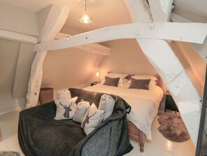Une chambre confortable située dans les combles, avec un lit, des oreillers et une couverture.