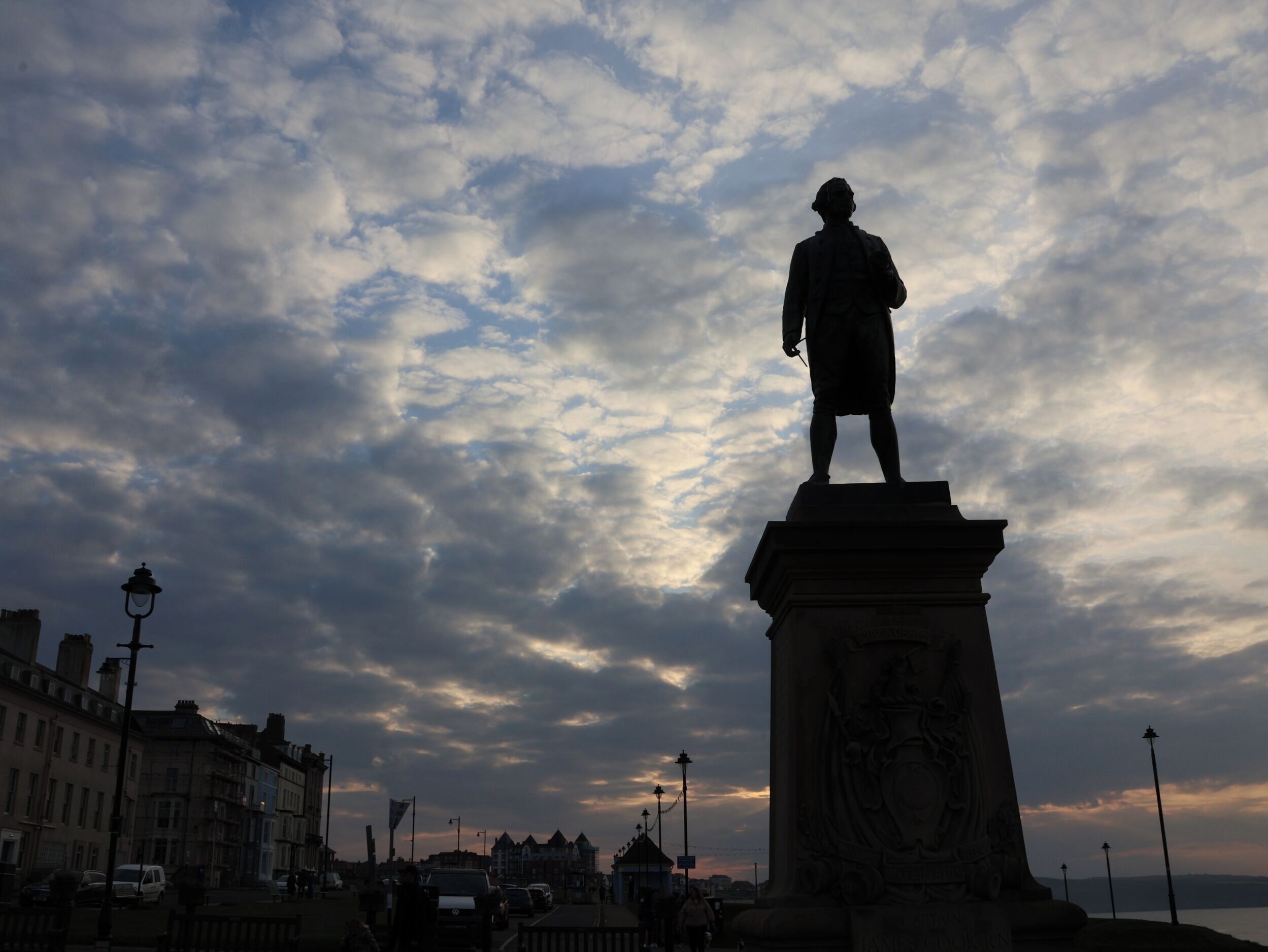 Una estatua sobre un pedestal, con un cielo nublado al fondo.