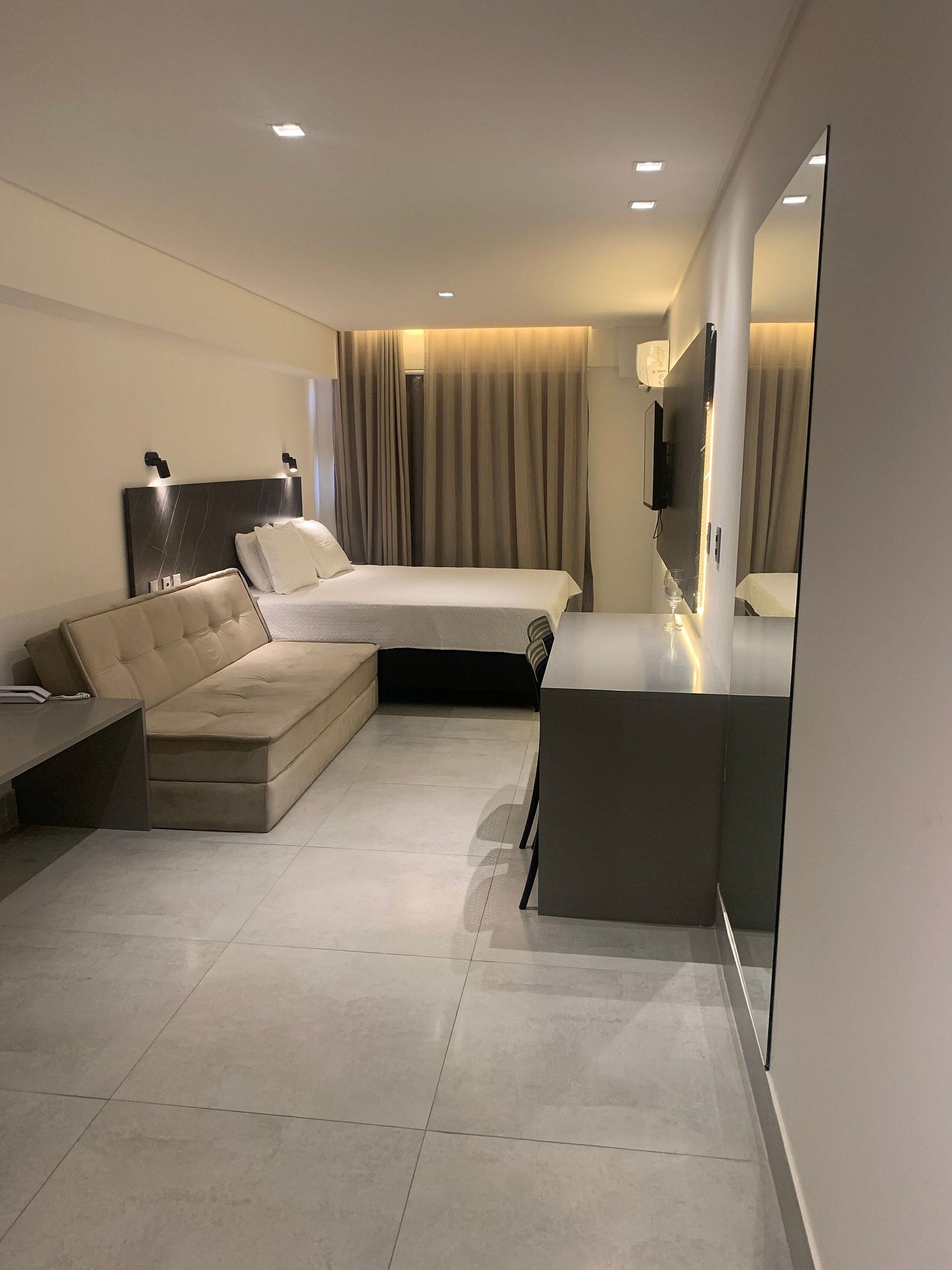 Een moderne hotelkamer met slaapbank, flatscreen televisie en een klein bureau.