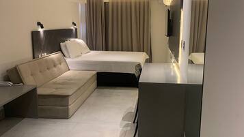 Een moderne hotelkamer met slaapbank, flatscreen televisie en een klein bureau.