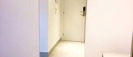 Um corredor com uma porta no fim, uma pequena janela e uma maçaneta.