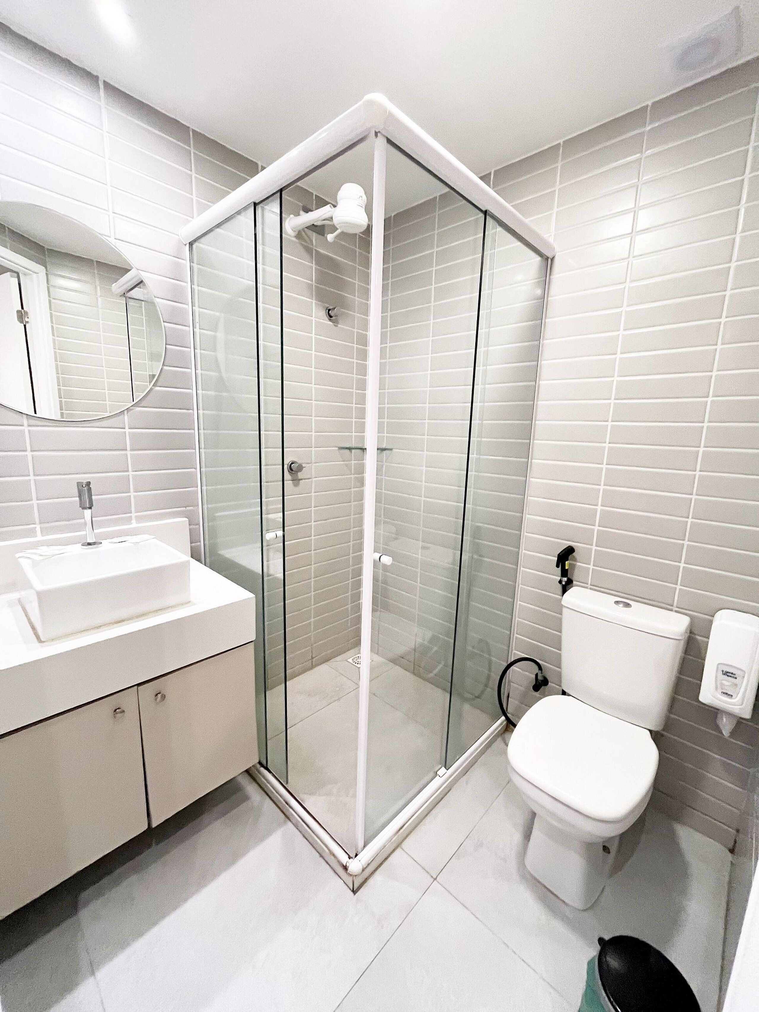 A modern bathroom with a glass-enclosed shower, a white sink, and a toilet.