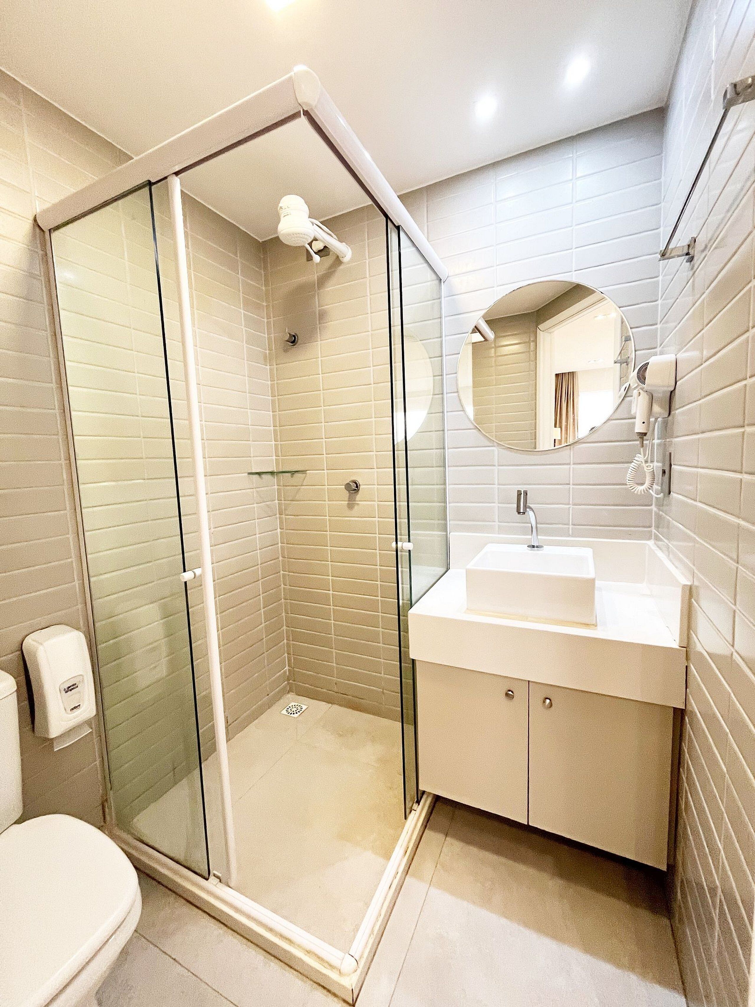 Een moderne badkamer met een douche met glazen wand, een wastafel met spiegel en een toilet.