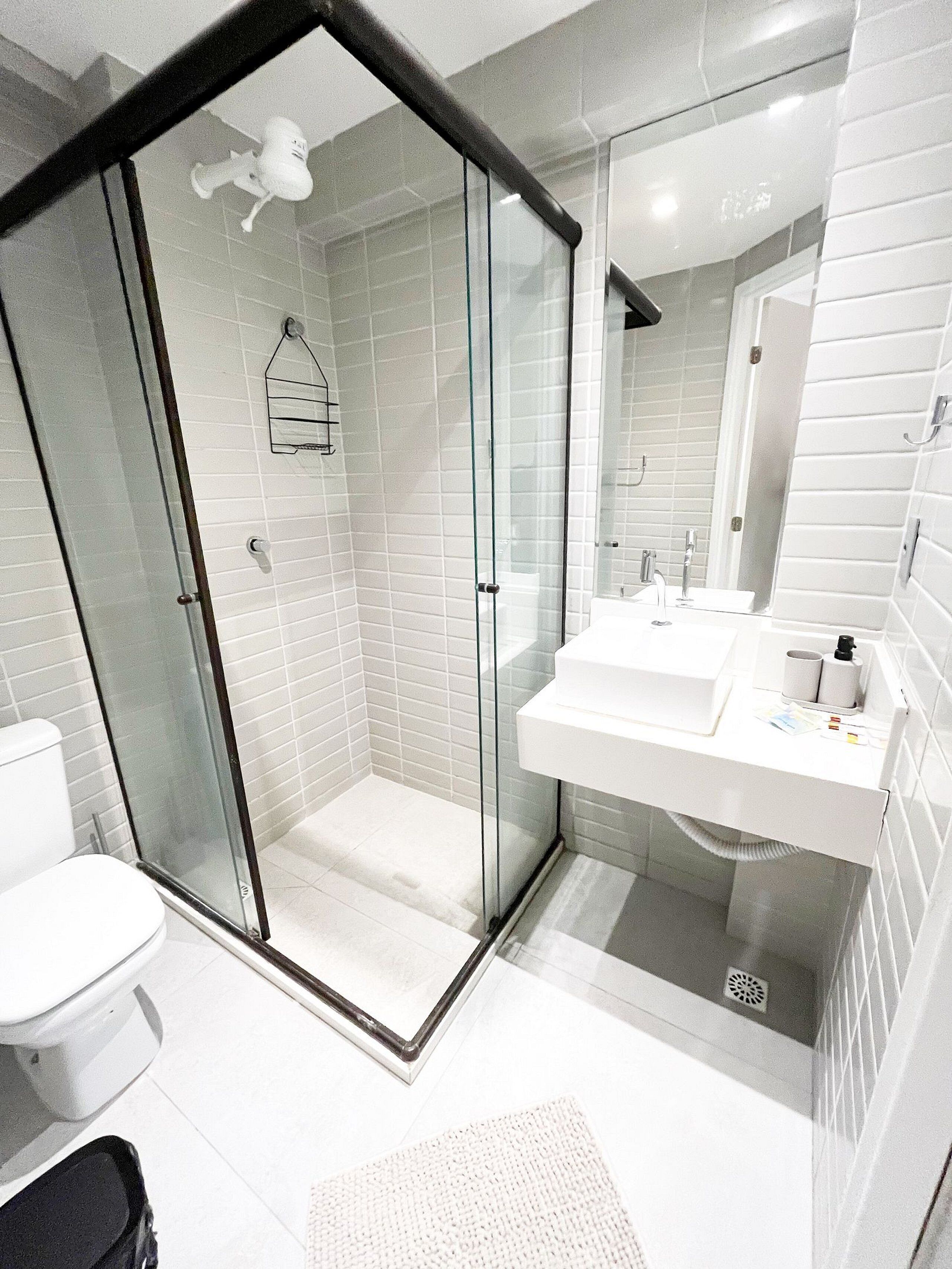 A modern bathroom with a glass-enclosed shower, a white sink, and a toilet.
