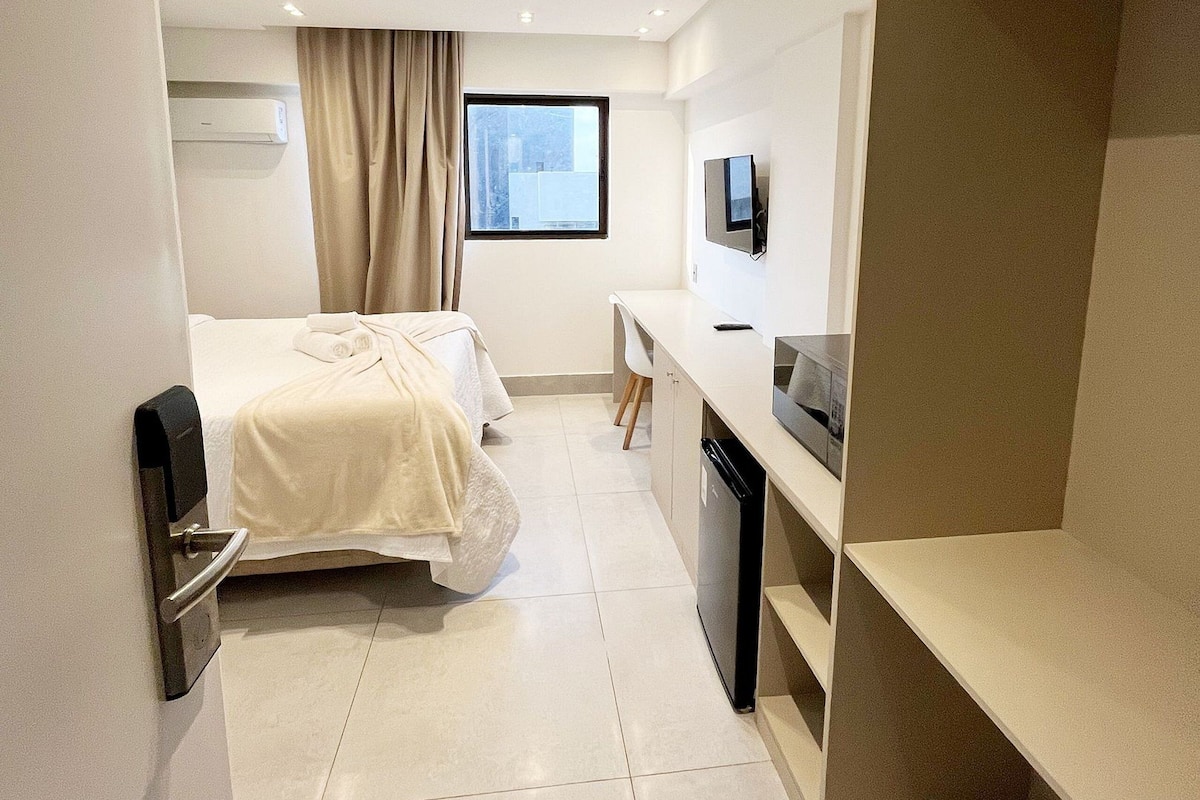 Habitación de hotel con cama, escritorio con televisor, armario y aire acondicionado.