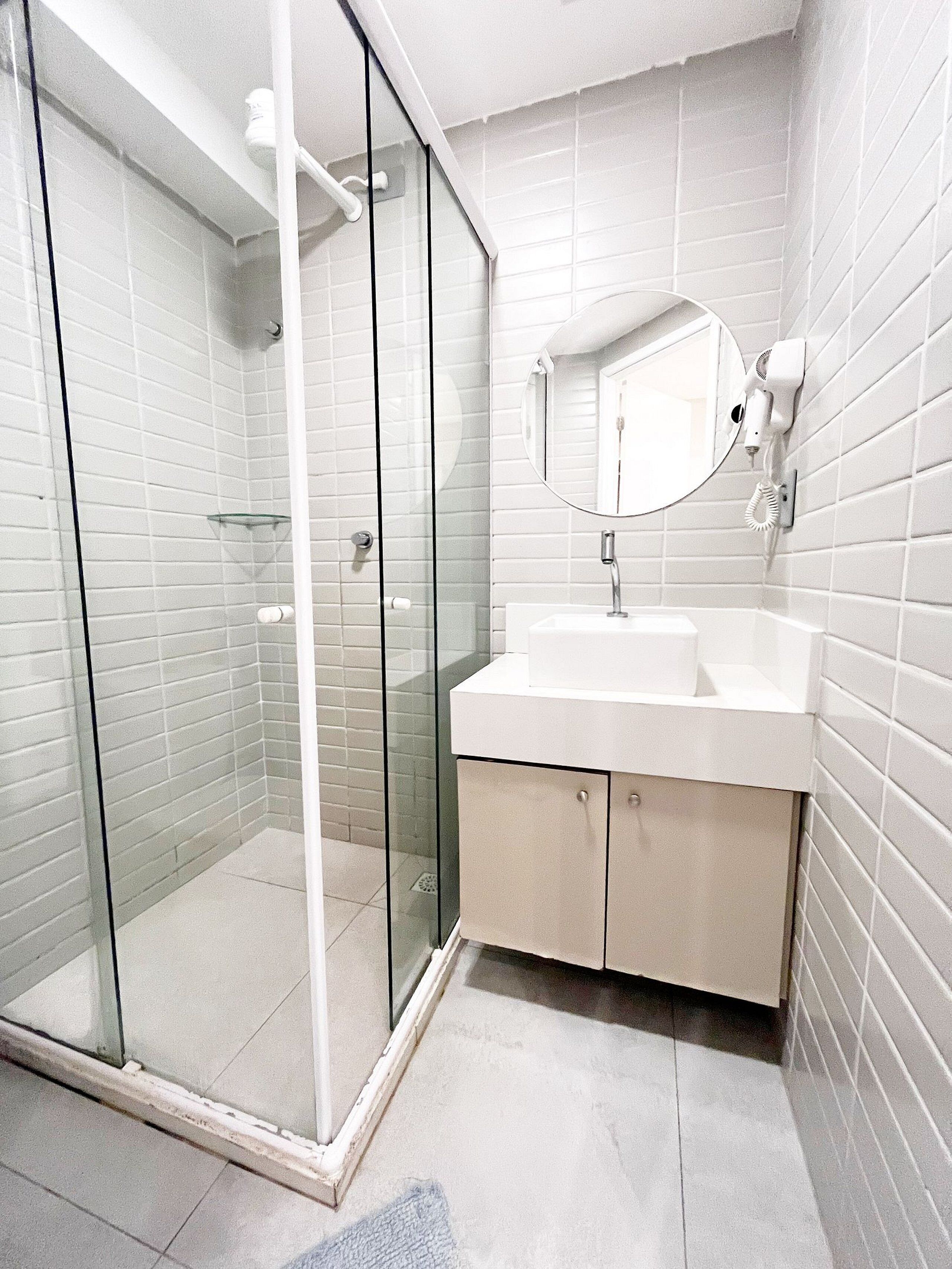 A modern bathroom with a glass shower enclosure, a white sink, and a mirror.