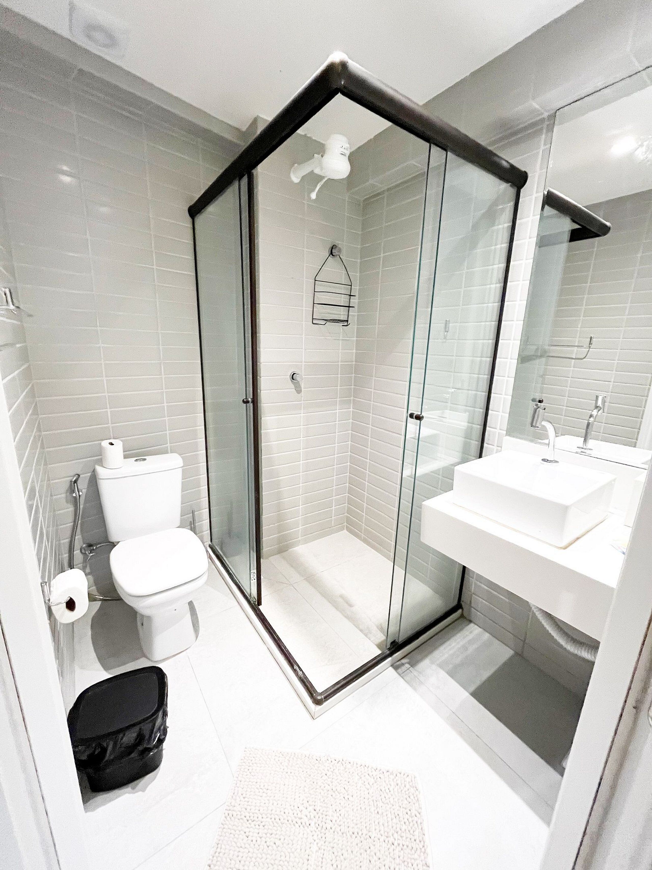 Un baño moderno con ducha envuelta en vidrio, inodoro y lavamanos.