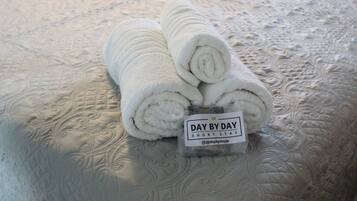 A rolled white towel with a label on a textured bedspread.
