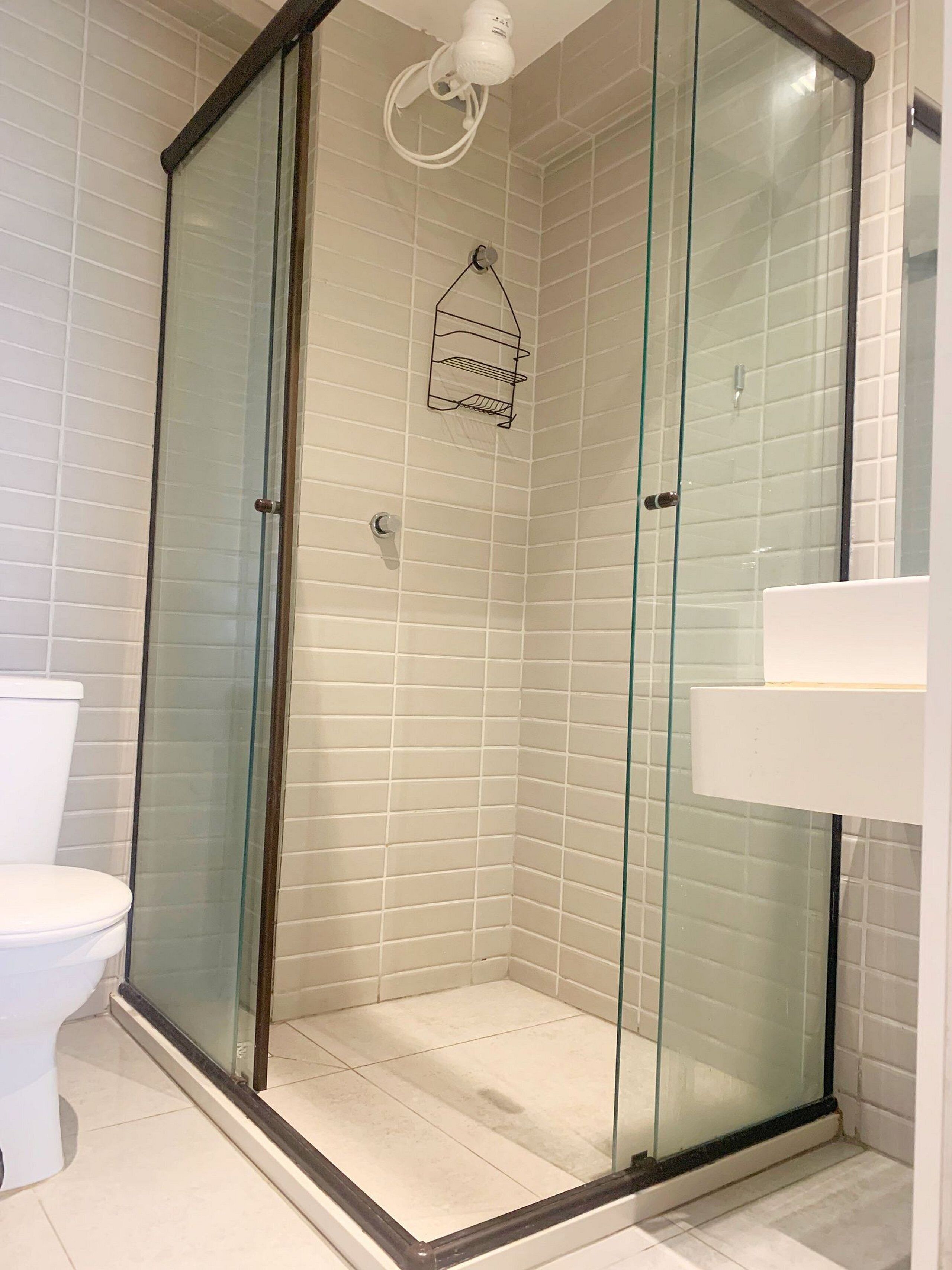 A glass-enclosed shower with white tiled walls and a white toilet visible to the left.