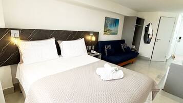 Una habitación de hotel con cama, mesita de noche, lámpara y un cuadro en la pared.