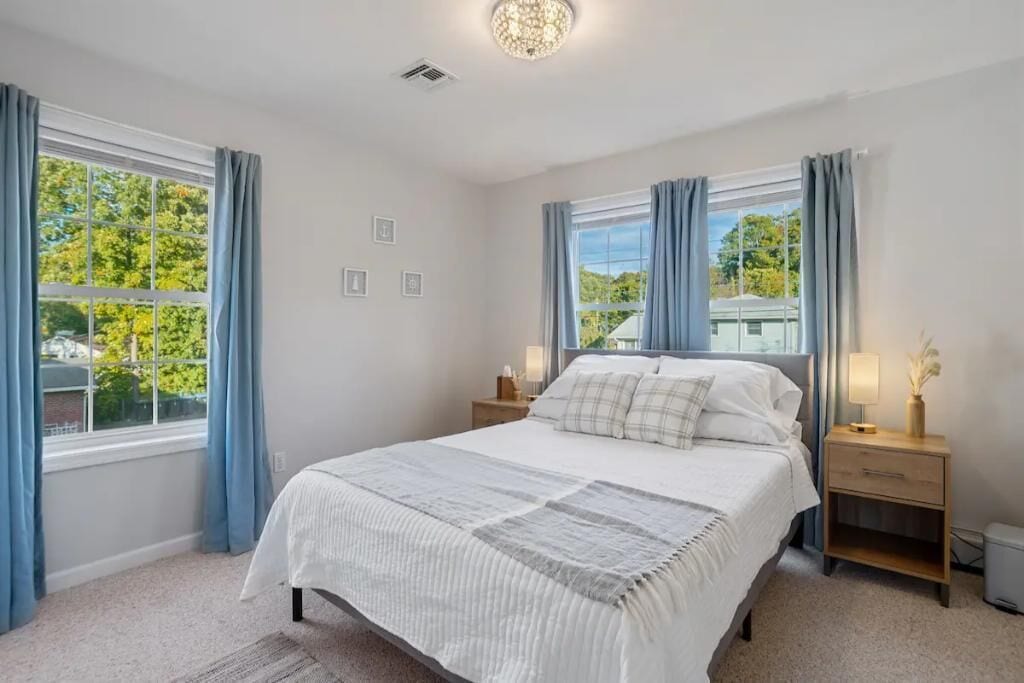 A bedroom with a large bed, two bedside tables, and a window with curtains.