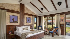 Une chambre spacieuse avec un grand lit, une tête de lit en bois et une vue sur l’extérieur grâce à une porte vitrée.