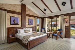 A spacious bedroom with a large bed, wooden headboard, and a view of the outdoors through a glass door.