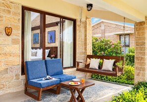 A room with a sofa, a swing, and a table with a plate and a glass of orange juice. - The Blackbuck Trails Velavadar (Bhavnagar)