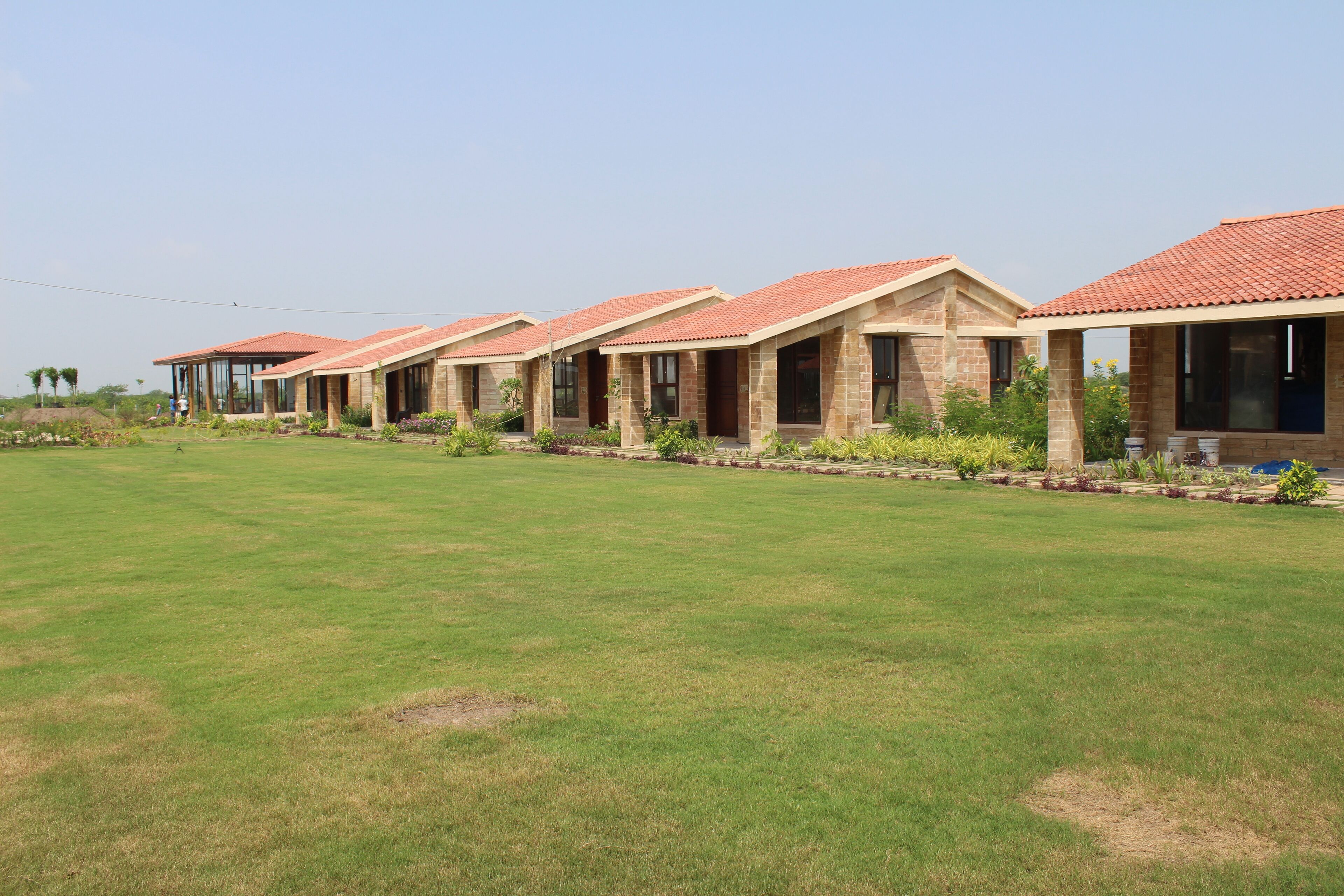 A row of modern buildings with tiled roofs and large windows, surrounded by a well-maintained lawn.