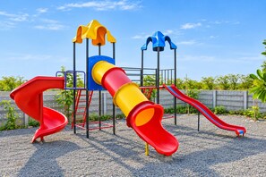 A playground with a slide, climbing structure, and a yellow and red tube slide. - The Blackbuck Trails Velavadar (Bhavnagar)