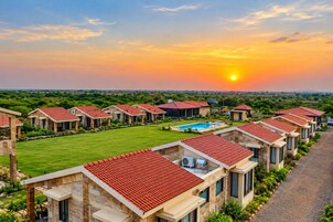 A resort with multiple villas, a swimming pool, and a clear view of the sunset.