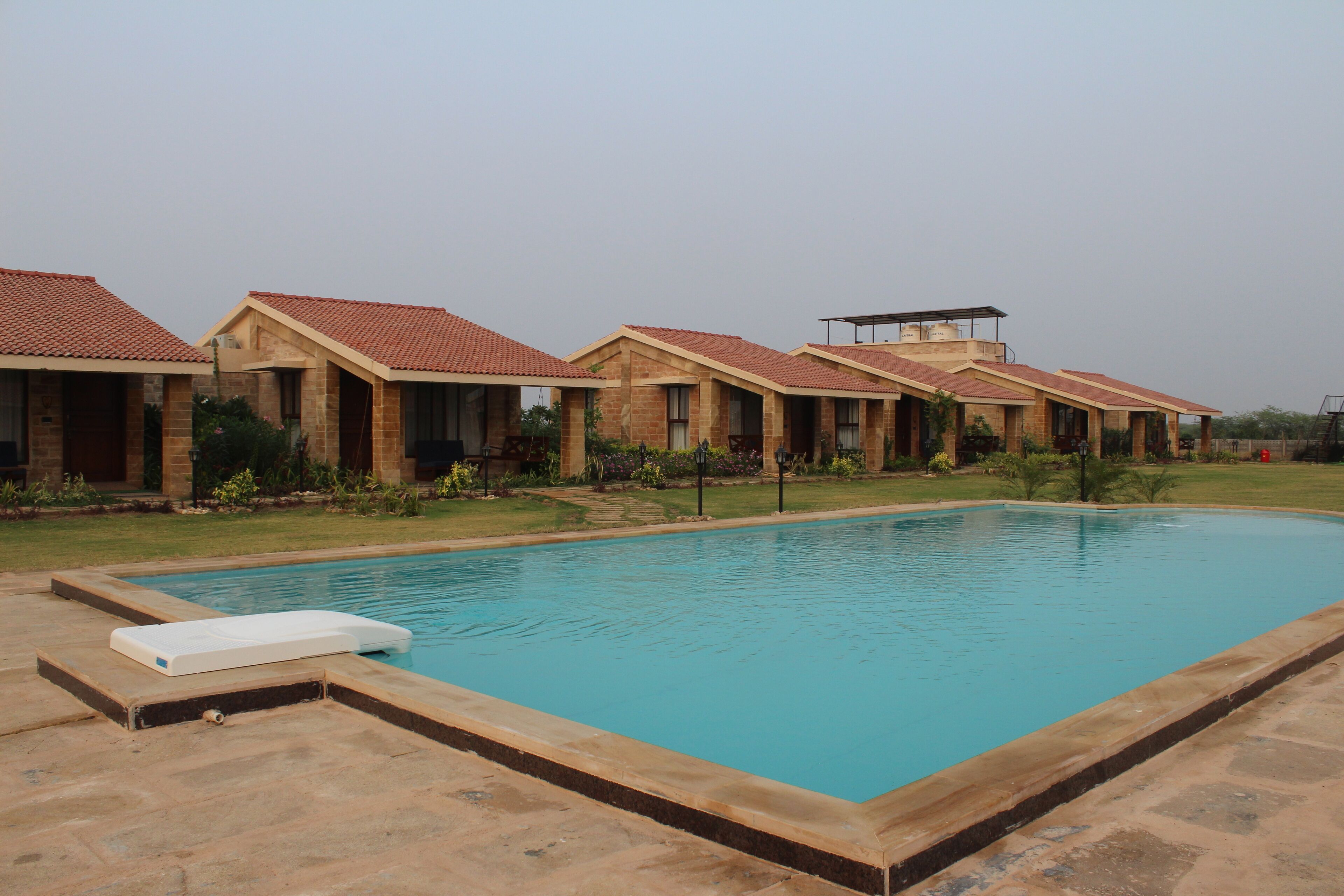 A pool area with a rectangular pool and a lounge chair.