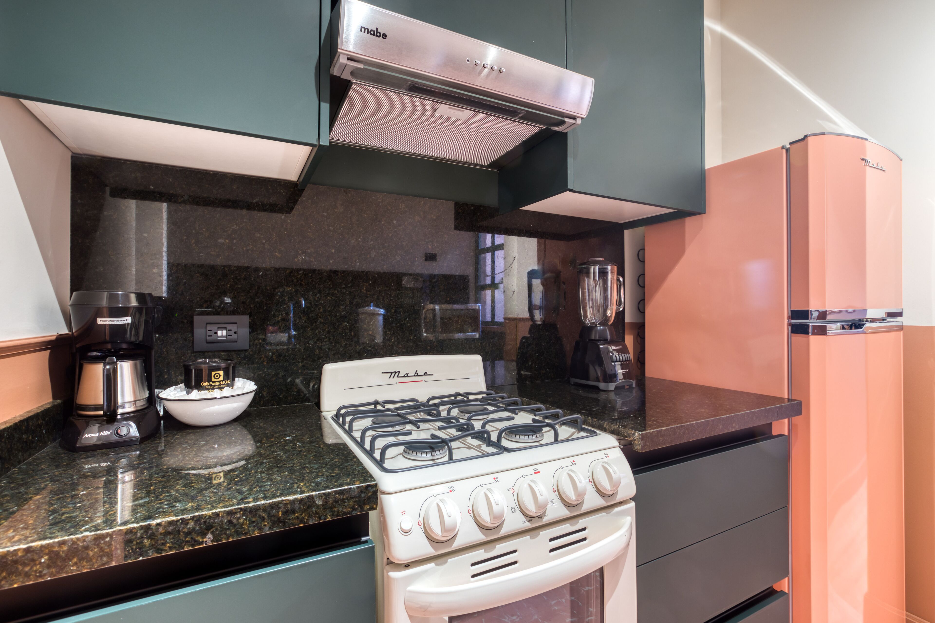 A kitchen with a white stove, a coffee maker, and a blender on the counter.