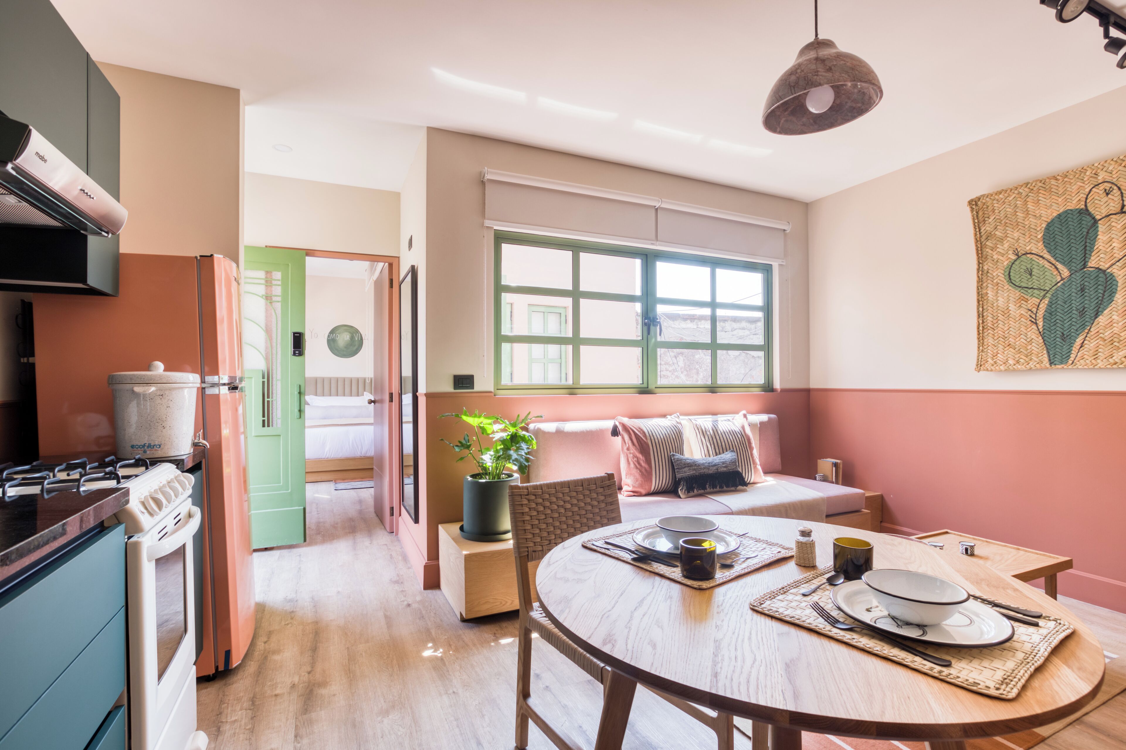 A compact kitchen with a stove, sink, and a dining area with a table set for two.