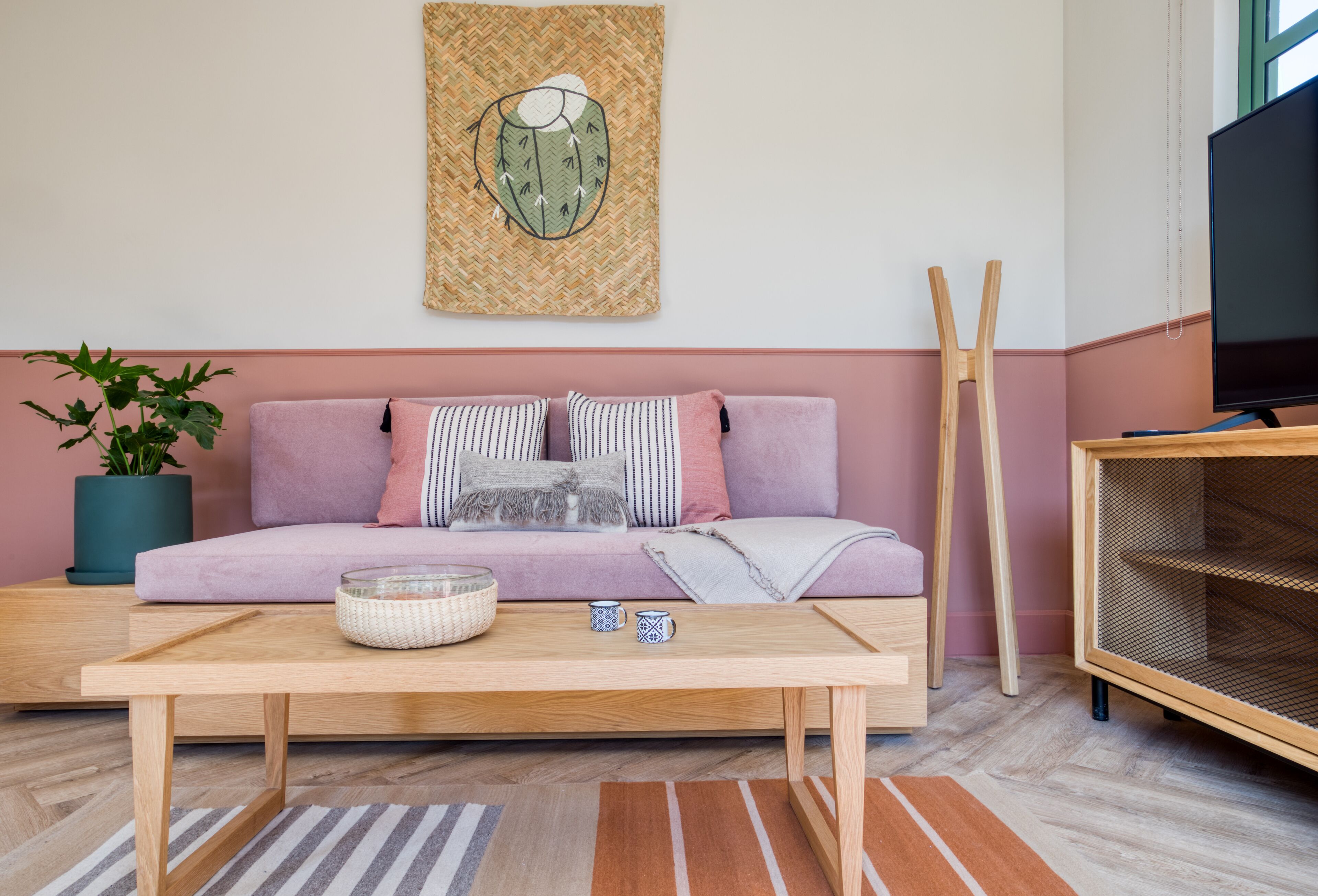 En stue med sofa, sofabord, fjernsyn og en plante.