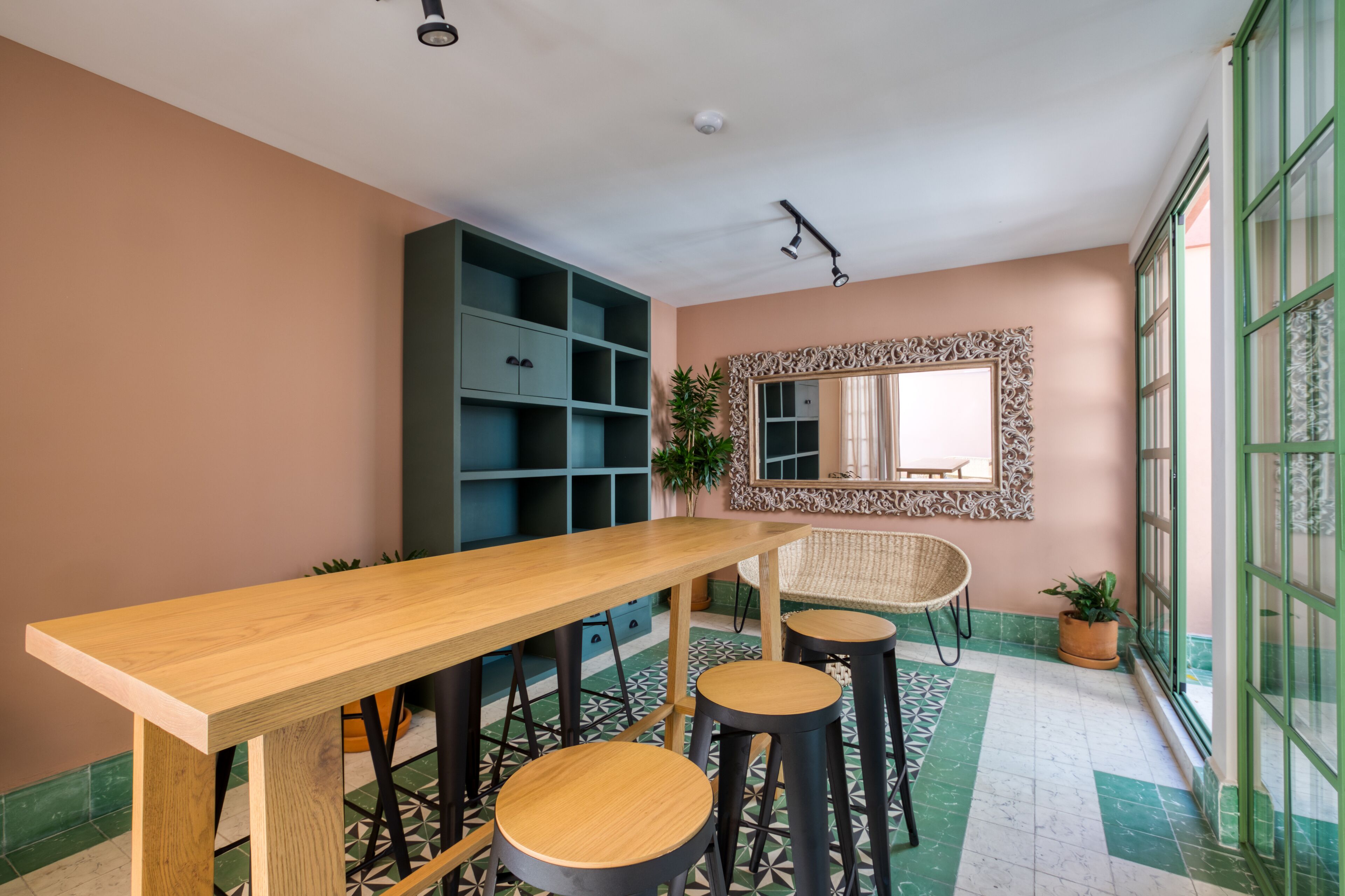 Una cucina moderna con un tavolo e sgabelli in legno, un armadio a incasso e uno specchio decorativo.