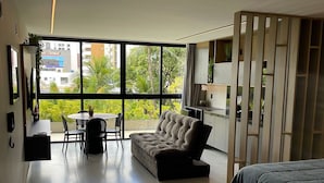 Un dormitorio moderno con una cama grande, un sofá, un comedor y vistas amplias a través de grandes ventanales.