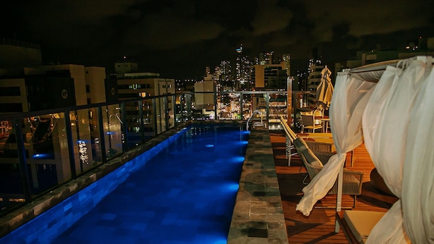 Una piscina en la azotea con vistas a la ciudad de noche.
