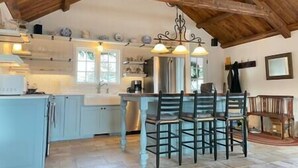 Una cucina con soffitto in legno, un'isola centrale con sedie e lampade a sospensione.