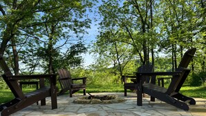 Un patio in pietra con poltrone Adirondack e un braciere.
