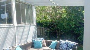 A covered patio with a sectional sofa, a pergola, and a view of the backyard.