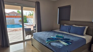 A hotel room with a bed, a view of a swimming pool, and a chair by the pool.