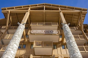 A multi-story building with a sign reading "ALPINA LODGE Residence Hotel".