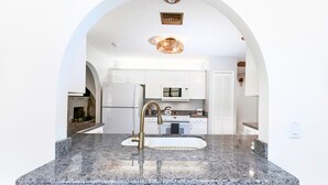A modern kitchen with granite countertops, stainless steel appliances, and white cabinetry. - Peaceful and Spacious Pool home in Jensen Beach! RV-Boat Prkg-Fenced Yrd (Jensen Beach)