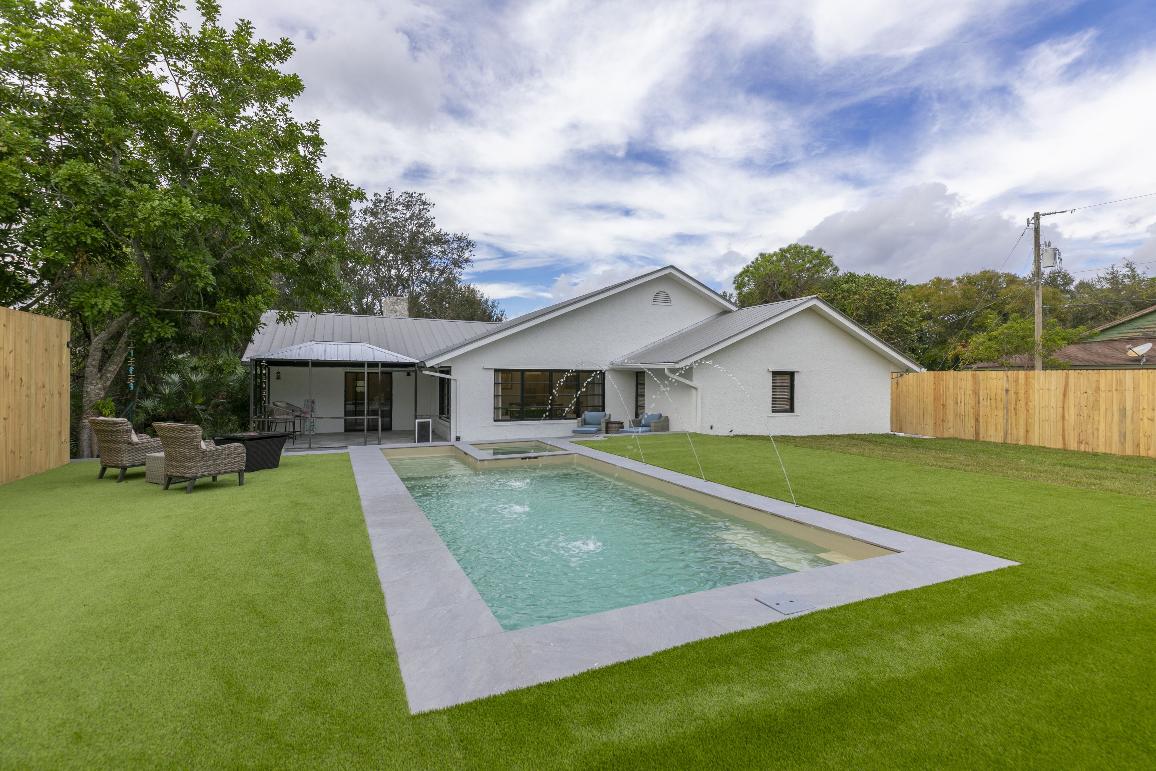 A modern house with a swimming pool, a covered patio, and a well-maintained lawn.