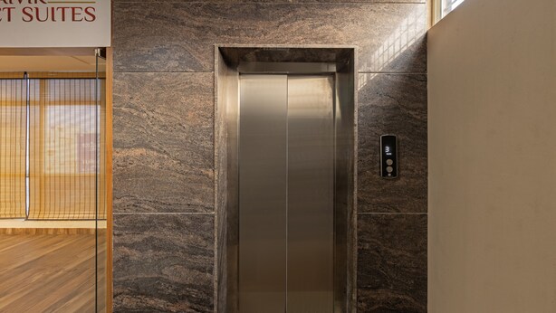 An elevator with a digital display, metallic walls, and a sign above indicating "AVENT SUITES".