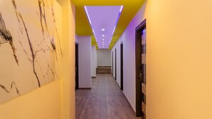 A hallway with marble walls, a wooden floor, and a staircase leading to an upper level.