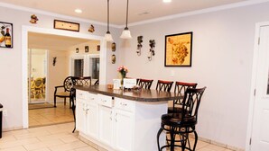 A kitchen with a central island, bar stools, white cabinets, and decorative wall art. - Cozy Country Retreat Ranch Style Home, private hot tub, pet friendly (Sanford)