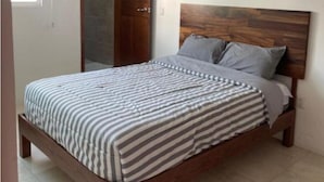 Une chambre à coucher avec un cadre de lit en bois, une couvre-lit à rayures et une tête de lit en bois.