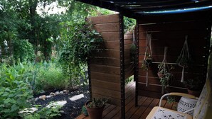 A wooden deck with a pergola, potted plants, and hanging macrame decorations.
