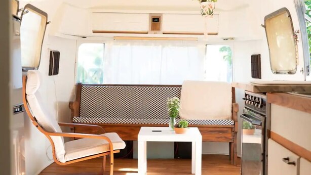 A compact RV interior with a seating area, a small table, and a kitchenette.
